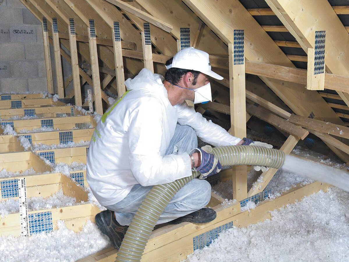 Technicien en intervention de soufflage de laine d'isolation dans des combles